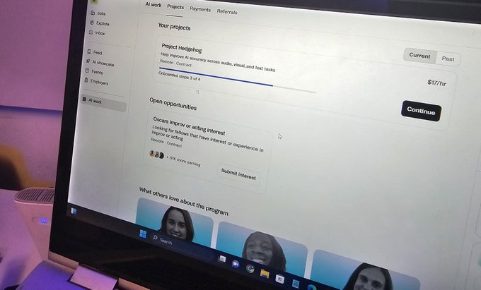 A computer monitor displaying the Upwork platform showing an 'AI work' dashboard with a current project titled 'Project Hedgehog' for AI accuracy testing at $17/hr and an open opportunity for 'Oscars improver or acting interest'.