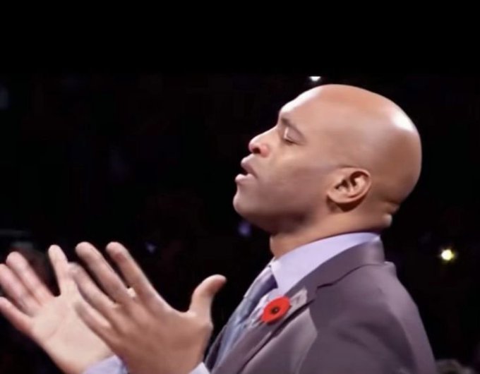 A bald man in a gray suit with a red poppy pin has his hands raised and eyes closed, appearing to be in a moment of celebration or gratitude. The image complements the post about a gambler's remarkable 417.45x win on Mines, suggesting the user is reacting to or celebrating the impressive $600K+ payout.