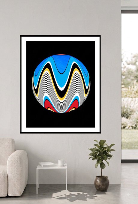 A framed poster on a white wall features an abstract, swirling sphere design in blue, black, red, white, and yellow colors above a small white side table and a potted plant.