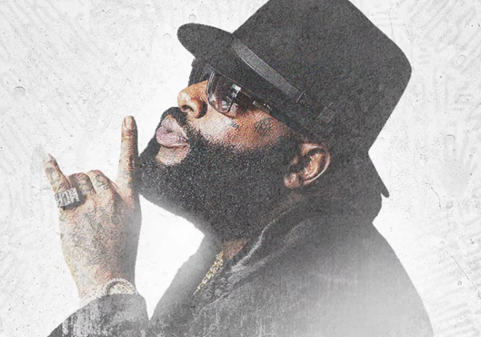 A bearded man wearing sunglasses and a black top hat points to a tattoo reading "Axius" near his eye, with his finger raised. The bold styling and central name tattoo visually reinforce the caption's boast about "Doctor Axius" as a confident, larger-than-life persona.