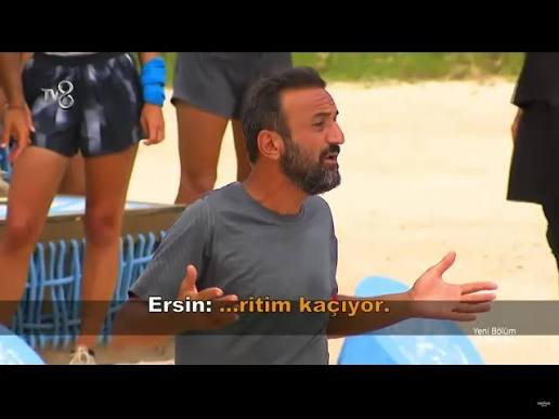 A bearded man in a gray t-shirt gestures with open hands, appearing frustrated or animated, while subtitles read "Ersin: ...ritim kaçıyor." The TV8 logo is visible, suggesting this is from a Turkish reality show, likely Survivor, where contestants often express heightened emotions during high-pressure competition moments.