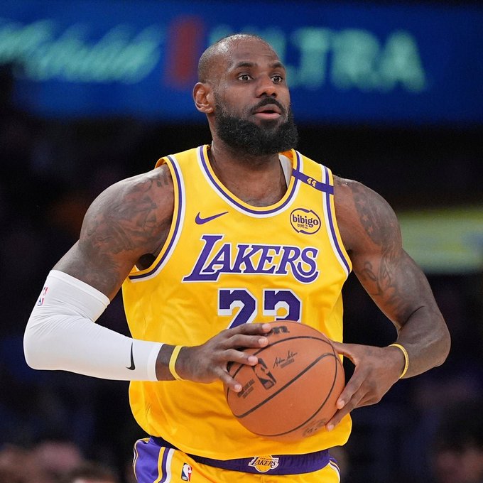 LeBron James, wearing his Lakers #23 jersey, holds a basketball on the court. The image relates to the post by visually identifying James as the subject of the rumored Robinhood launch announcement.