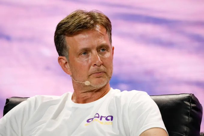 The image features a man wearing a white t-shirt with purple text, sitting in a chair and looking off into the distance. He has a microphone attached to his ear, suggesting that he might be participating in an event or discussion related to cryptocurrency. The caption provided about tokenization potentially overtaking Bitcoin as the biggest story in crypto is relevant to this scene, as it could indicate that the man's involvement in the conversation is connected to the topic of tokenization and its impact on the cryptocurrency market.

The image also includes a purple background with some text written on it, which may be related to the discussion or event taking place. The overall atmosphere suggests an intellectual gathering where various topics are being discussed, including the potential future of Bitcoin and the broader implications of tokenization in the crypto world.