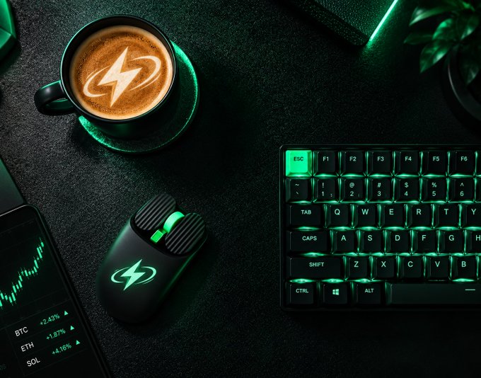 A green-lit gaming/tech desk setup featuring a coffee cup with a lightning bolt logo, a Razer gaming mouse, a mechanical keyboard, and a phone displaying crypto prices including BTC, ETH, and SOL.