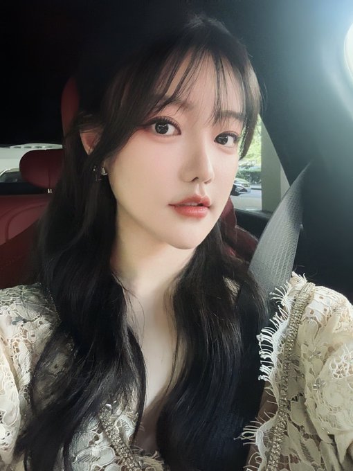 A young woman with long dark hair sits in the driver's seat of a car, wearing a delicate lace top and looking at the camera. The image relates to the post by capturing a moment of confidence and anticipation, paralleling the excitement of returning to the crypto market and the thrill of high-performing grid bots exceeding price ranges.