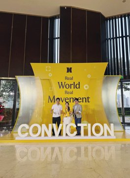 Three individuals pose on a stage in front of a large yellow and white branded backdrop displaying "Real World Movement" and "CONVICTION," with three prominent illuminated letters spelling out the event's name. The image ties to the post by capturing participants at Conviction 2026, the conference where chain strategies for the agentic economy—including Aptos Foundation's infrastructure and stablecoin payment developments—are being discussed.