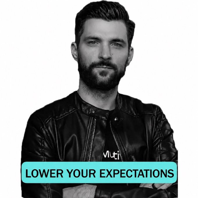 A black-and-white photo of a bearded man in a leather jacket stares seriously at the camera with his arms crossed, accompanied by a teal banner reading "LOWER YOUR EXPECTATIONS." The caption humorously underscores the post's skeptical forecast of only a 3% chance for the Supernova $EGLD launch on September 10th, advising followers not to hold their hopes too high.