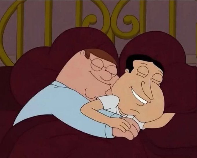 An animated scene from Family Guy showing Peter Griffin and Joe Swanson cuddling together in bed, both smiling contentedly.