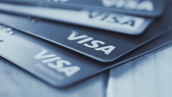 A close-up of several stacked dark blue Visa Platinum credit cards with the embossed Visa logo prominently displayed.