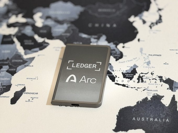 A Ledger hardware device displaying the 'Arc' logo rests on a world map.