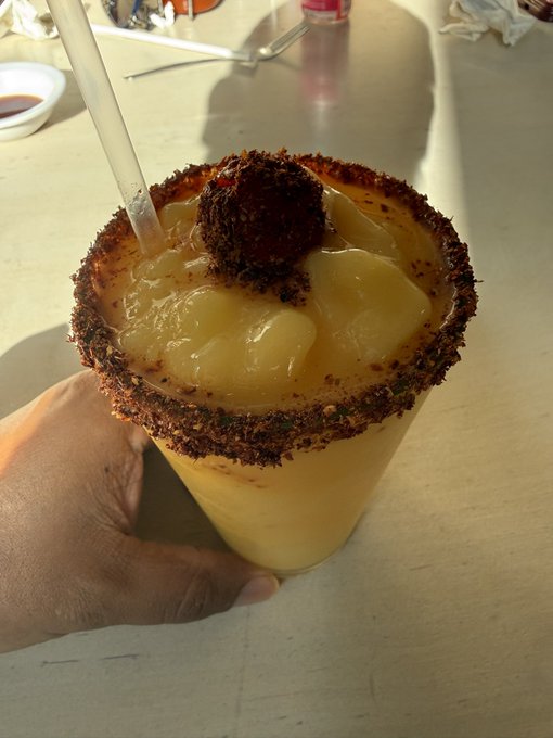 iced coffee with a brown sugar ball on top, garnished with a cinnamon stick and straw.