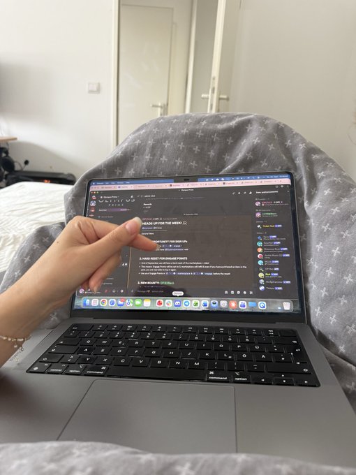 A hand rests on a laptop keyboard displaying a dark-themed Discord server, with numbered menu options visible on the screen.