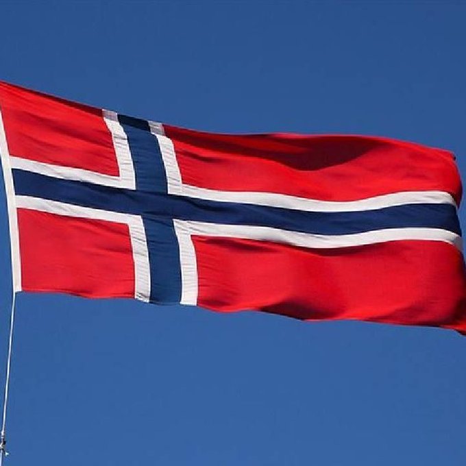 The Norwegian flag waves against a clear blue sky. This relates to the post about Norway's Government Pension Fund's investment holdings, as the fund is managed by the Norwegian government.
