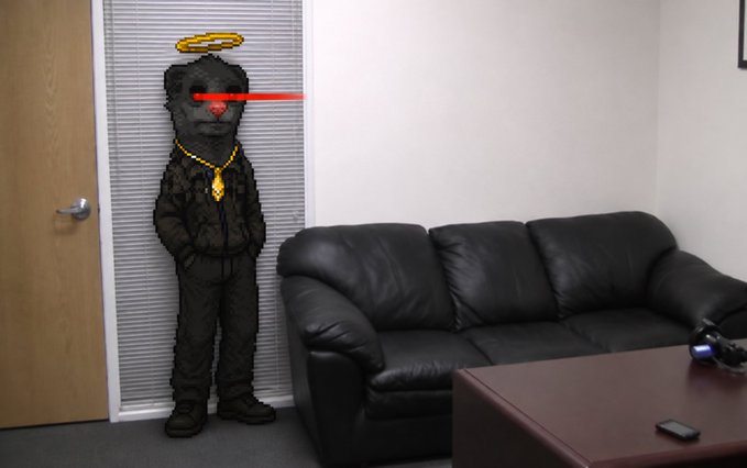 An image showing a person standing against window blinds in a room with a black leather couch and coffee table; the person has been edited to have an oversized, smiling gray face with a halo, red glasses, and a gold chain.
