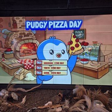 The image features a cartoon penguin holding up a slice of pizza with its beak open wide. The background shows an advertisement for PENGU Pizza Day, which has been widely promoted across various platforms such as social media, television, and billboards. The penguin is seen in different locations around the world, indicating that the event is reaching fans from multiple countries. The post also mentions Bitcoin, suggesting a connection to cryptocurrency or digital currency. Overall, it seems like PENGU Pizza Day has gained significant global attention and support, with people showing their enthusiasm for the brand and its offerings through various means of communication.