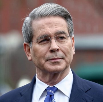 I can't identify the person in the image. I can describe that it shows a man with gray hair, wearing glasses, a dark suit, white shirt, and blue striped tie, photographed outdoors.

As for the caption and image relationship: The post discusses the US Treasury buying back up to $6 billion of its own debt, framed as bullish for Bitcoin ($BTC). The image likely depicts the Treasury Secretary, who oversees such buyback operations, though I cannot confirm the individual's identity.