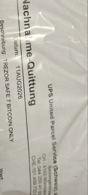 A shipping receipt or waybill with German text, including 'Nachnahme-Quittung', a date of '11 AUG 2026', and Bitcoin payment instructions referencing 'TREZOR SAFE 7 BITCOIN ONLY'.