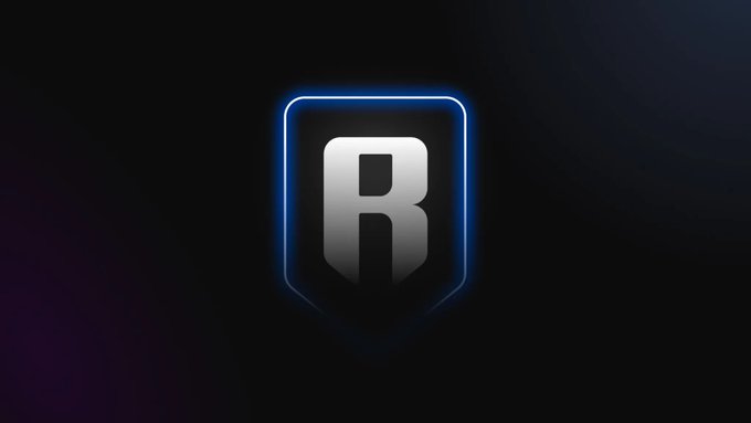 The image shows the Ronin Wallet logo, featuring a bold white "R" inside a glowing blue shield-shaped emblem against a dark background. This logo represents the Ronin Wallet platform mentioned in the post, which has restored its "Buy Crypto" functionality through the + Fund feature after a period of unavailability due to updates.