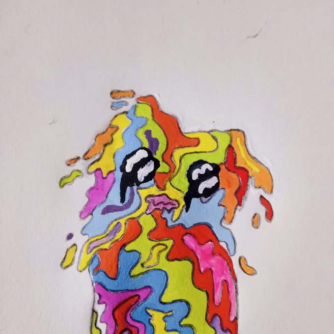 A colorful abstract marker drawing of a cat or kitten figure with large expressive eyes, rendered in vibrant patches of yellow, red, blue, green, pink, and orange on white paper.
