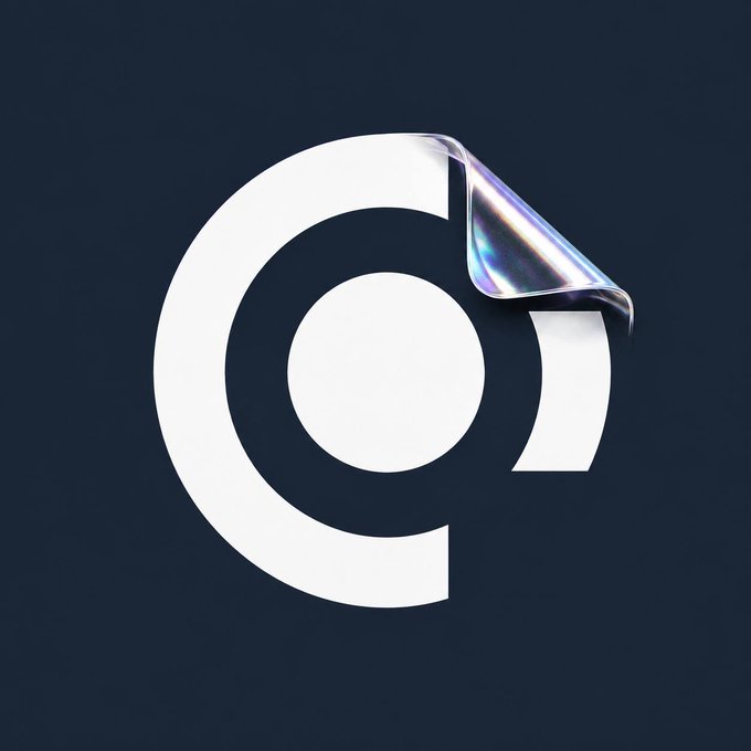 A white circular logo resembling a 'C' or '@' symbol on a dark navy background, with a metallic chrome peeling effect in the upper right corner revealing a shiny, iridescent underside.