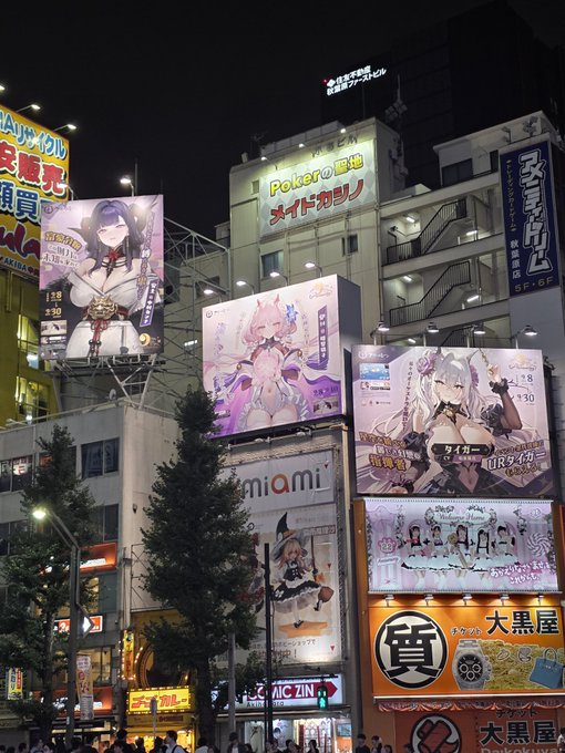 A nighttime cityscape features brightly lit buildings and large billboards advertising anime characters and Japanese restaurants, including signage for 'Polero' and 'Miami'.