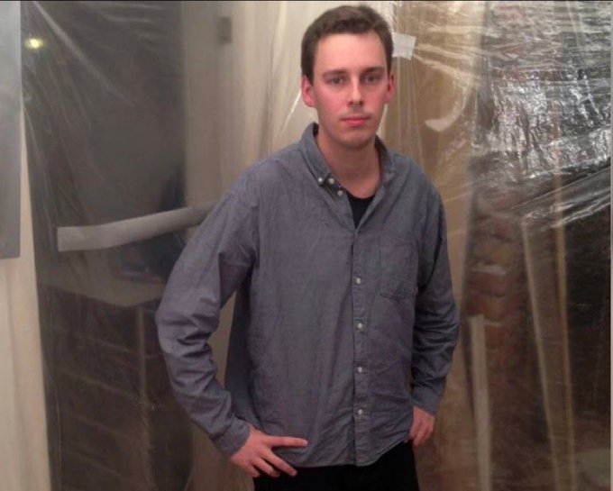 A young man, presumably Kristoffer Koch, stands in a room with plastic-covered walls, wearing a blue button-down shirt with his hands on his hips. The image accompanies the story of how he accidentally turned $27 into a fortune by purchasing 5,000 Bitcoin in 2009 while researching cryptography for educational purposes.