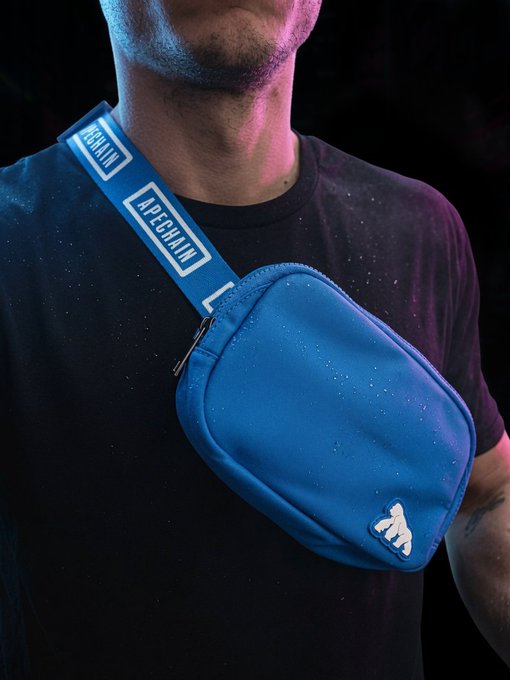 A product photo of a person wearing a black t-shirt with a blue APECHAIN crossbody sling bag featuring a white mountain logo on the strap and bag.