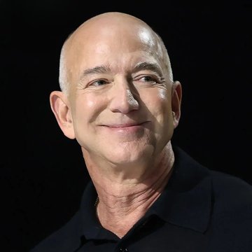 A close-up portrait of Jeff Bezos, founder of Amazon, smiling slightly with a bald head against a black background.