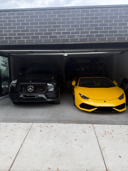 Two luxury vehicles—a black Mercedes-Benz SUV and a yellow Lamborghini Huracán—are parked side by side in a modern garage, serving as visual proof of the poster's success after leaving a 9-to-5 job to go "all in on crypto" and build wealth by age 28.