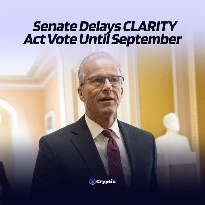 The image shows a man in a dark suit, white shirt, and maroon tie wearing glasses, standing in what appears to be a government building hallway, with the headline "Senate Delays CLARITY Act Vote Until September" displayed above him and the "Cryptic" logo at the bottom, illustrating the news about the delayed vote on the crypto market structure bill.