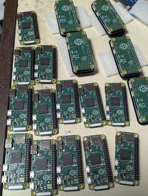 Multiple green Raspberry Pi Zero single-board computers are arranged on a workbench, showing both bare circuit boards and several in protective cases.