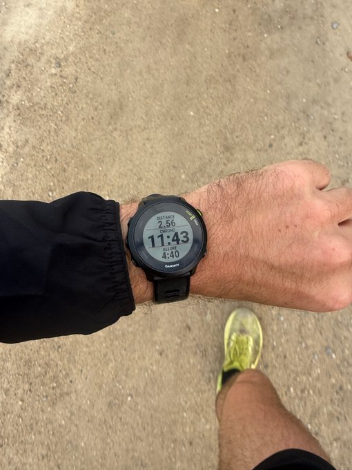 A close-up of a Garmin smartwatch on a wrist during a run, showing "Distance 2.56", "Chrono 11:43", and "Allure 4:40".