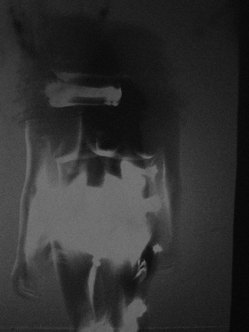 This grainy, dark image depicts a faint, x-ray-like silhouette of a woman, visually echoing the text "A woman who doesn't exist" associated with the Objkt platform.