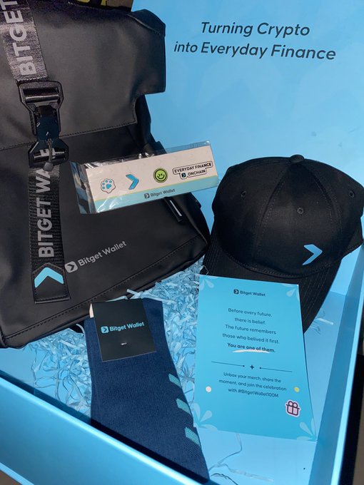 Bitget Wallet branded merchandise including a black backpack, cap, socks, and informational cards displayed in a promotional box with the tagline "Turning Crypto into Everyday Finance." The items align with the user's excitement about receiving the swag, showcasing the "EVERYDAY FINANCE, NOCHAINS" branding on the cards and celebrating Bitget Wallet's 100M milestone.