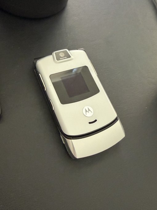 The image features an old, silver flip phone placed on a black surface. The phone appears to be turned off or not currently in use. The background of the photo includes text that reads "I'm about to make a call on the Ethereum network". This suggests that someone might be preparing for a phone call related to cryptocurrency or blockchain technology.