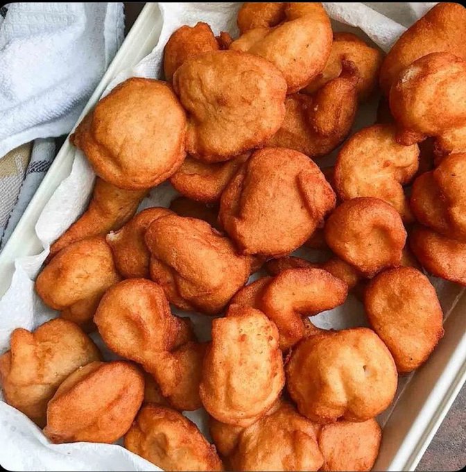 A close-up of golden-brown fried fritters piled in a paper towel-lined tray.