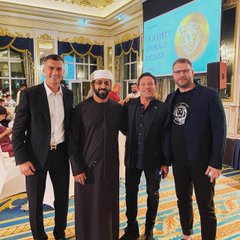 The post's caption about closing a Dubai-based crypto company aligns with the image showing four men posing together, including one in traditional Emirati attire, at what appears to be a formal event in a luxurious venue with a "Dubai Crypto Club" banner visible in the background.
