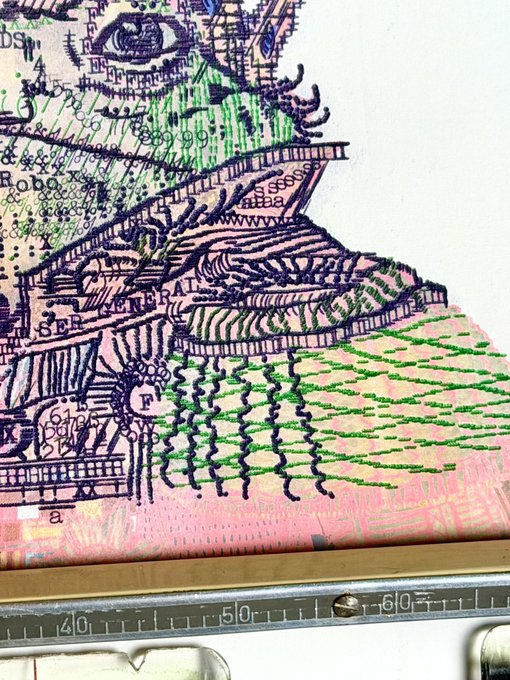A close-up of a mixed-media artwork on paper, featuring intricate dark purple and green linework resembling a map or collage with text fragments like 'GENERAL' and 'BER', sitting above a ruler.
