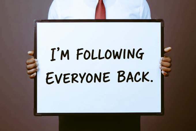 A person in a white shirt and red tie holds up a whiteboard with the handwritten message "I'M FOLLOWING EVERYONE BACK."