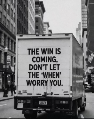 A black and white photo of a delivery truck driving down a city street, with the back displaying the message: 'THE WIN IS COMING, DON'T LET THE 'WHEN' WORRY YOU.'