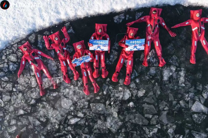 An aerial view captures seven people in red survival suits lying on cracked ice floes, with two holding signs reading "冰封暴徒" (Ice-Sealed Outlaws), symbolizing the team's resilience and unity in a harsh environment, reflecting the post's gratitude to "Brother Cha" for his 14 years of dedication and trust in the HTX team.