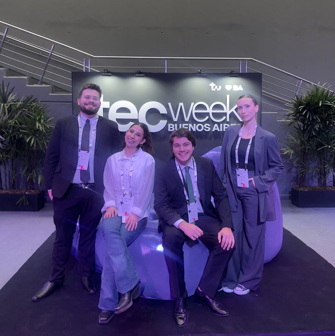 Four people pose in business attire at a “tech week BUENOS AIRES” event backdrop with the TU and BEA logos.
