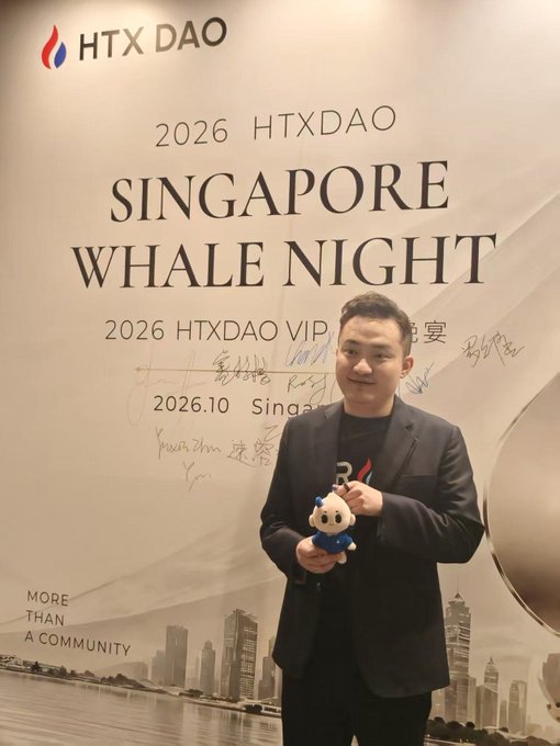 Justin Sun poses with a small plush mascot in front of a "2026 HTXDAO Singapore Whale Night" event backdrop dated 2026.10, commemorating a VIP event hosted by HTX DAO.