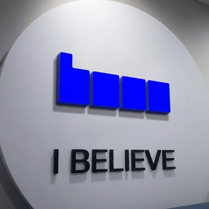 The image features a large white sign with blue letters that reads "I believe". The sign is displayed prominently, possibly at an office or a public space where people gather. The background of the image appears to be a wall, which further emphasizes the prominence of the sign and its message.