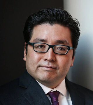 The image depicts a man wearing glasses, dressed in a suit with a tie around his neck, standing against a background that looks like an office setting or conference room. A small portion of text reading "BREAKING: Tom Lee's Bitmine just bought another $52.62 Million worth of Bitcoin" is visible within the frame. The image is likely a post on social media related to the cryptocurrency market or the news about BitCoin's value, emphasizing its recent purchase and market dominance by the company.