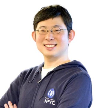 A portrait of a smiling East Asian man with glasses wearing a dark blue hoodie with a 'JpYC' logo, photographed against a white background.
