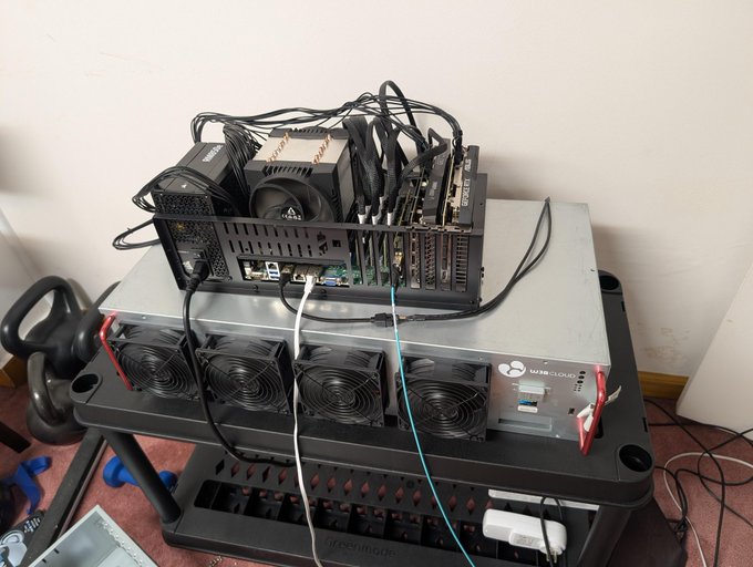 A cryptocurrency mining rig setup featuring multiple GPUs, cooling fans, and a power supply unit stacked on a plastic shelf, alongside exercise equipment.