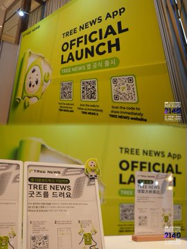 An official launch display for 'TREE NEWS APP' featuring a green mascot character, QR codes for download, and text in both English and Korean announcing the app's official release.