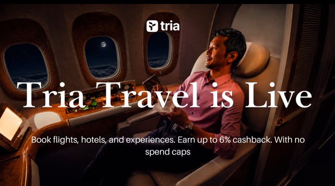 The image features a man sitting in an airplane seat, with the text "Tria Travel is Live" displayed above him. The background of the image shows the interior of an airplane cabin, which includes windows that provide a view of the sky outside. The focus on the man and his surroundings suggests that this post is promoting a travel-related service or product, possibly related to cryptocurrency or digital wallets for travel purposes.