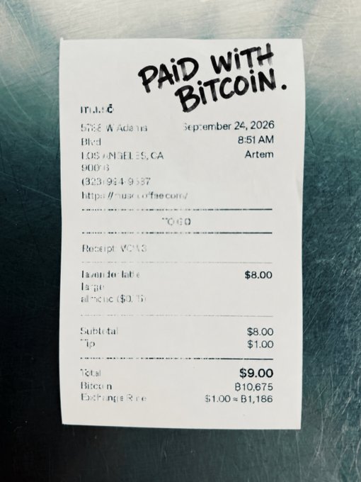 A coffee receipt stamped with "PAID WITH BITCOIN" sits on a metal counter, showing a $9.00 total (including $1 tip) paid with 0.001675 BTC at a $1,186 exchange rate, humorously proving the post's claim that "Everything's better with Bitcoin."